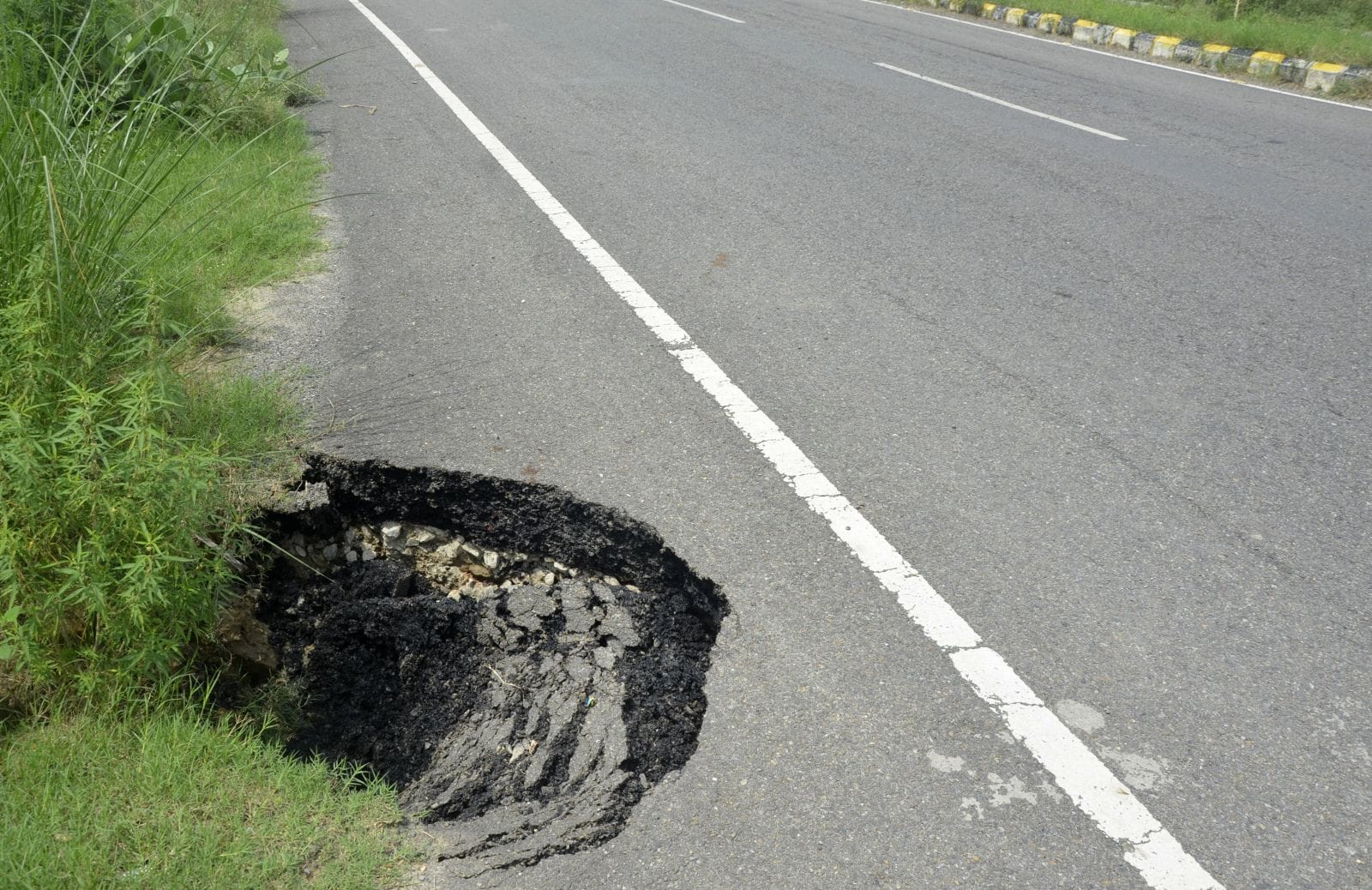 शहर के वाईपास पर बरसात से टूटी सड़क। संवाद
