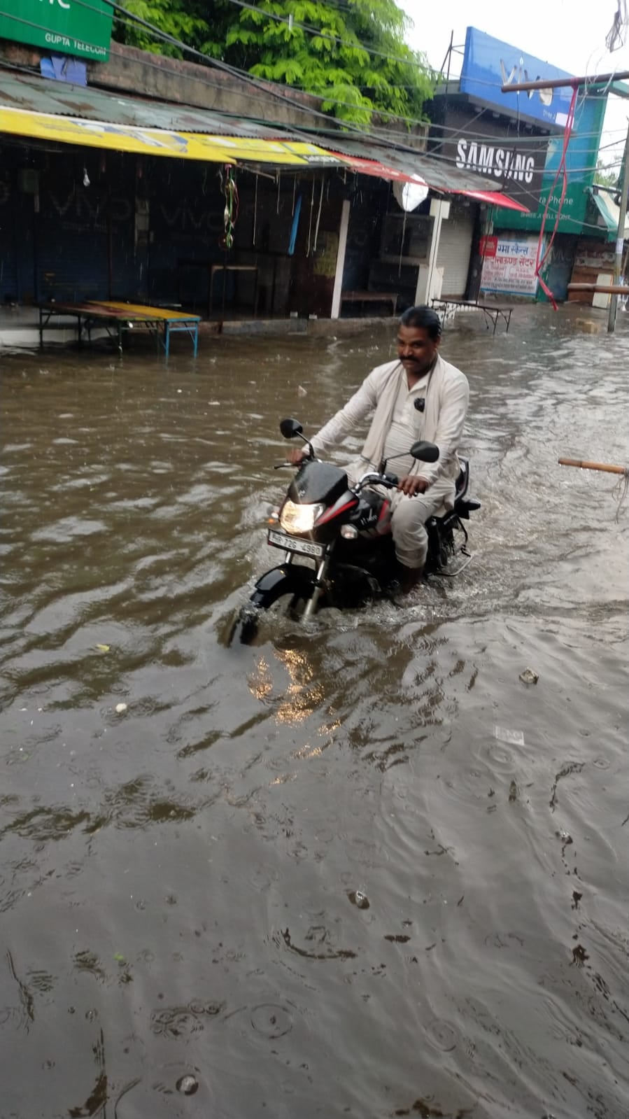 सोहना में हुई बरसात के दौरान सड़क पर भरे पानी से निकलते लोग। सोहना में हुई बरसात के दौरान सड़क पर भरे पानी से निकलते लोग।
