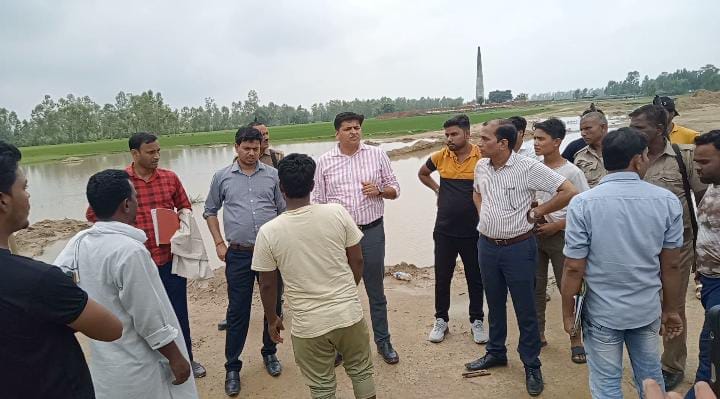 पानी भरे गड्डे की नाप करता ग्रामीण । संवाद