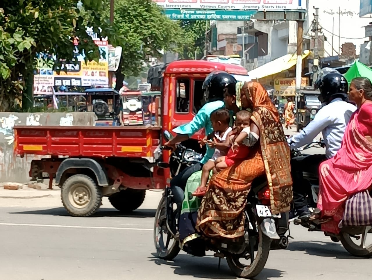 शहर में बाइक पर तीन सवारी बैठा कर ले जाते लोग । संवाद