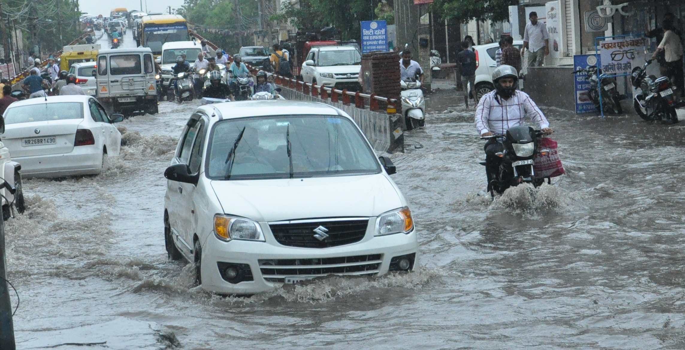 हिसार में बारिश के दौरान पुलिसकर्मी की स्कूटी बंद हुई तो मदद करता एक युवक। हिसार में बारिश के दौरान पुलिसकर्मी की स्कूटी बंद हुई तो मदद करता एक युवक।
