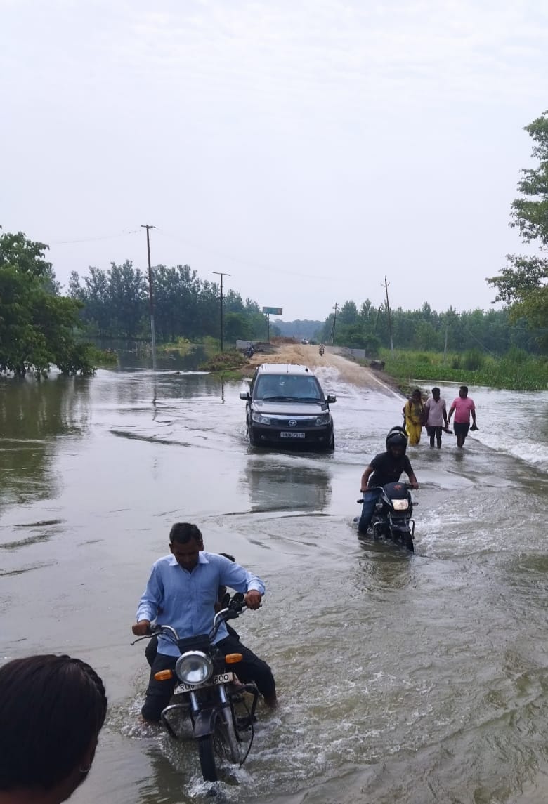 पुरकाजी के खादर क्षेत्र के गांव में भरे पानी से गुजरते ग्रामीण पुरकाजी के खादर क्षेत्र के गांव में भरे पानी से गुजरते ग्रामीण