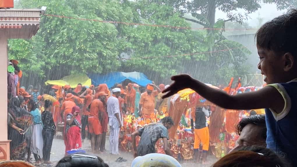 शहर में सोमवार की दोपहर हुई बारिश में छाता लगाकर जाता युवक । संवाद