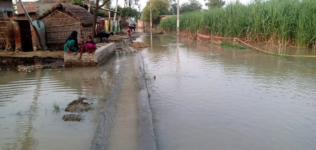 मिर्जापुर के जलमग्न ग्राम पैलानी में चारपाई पर भूसा ले जाते युवक। संवाद