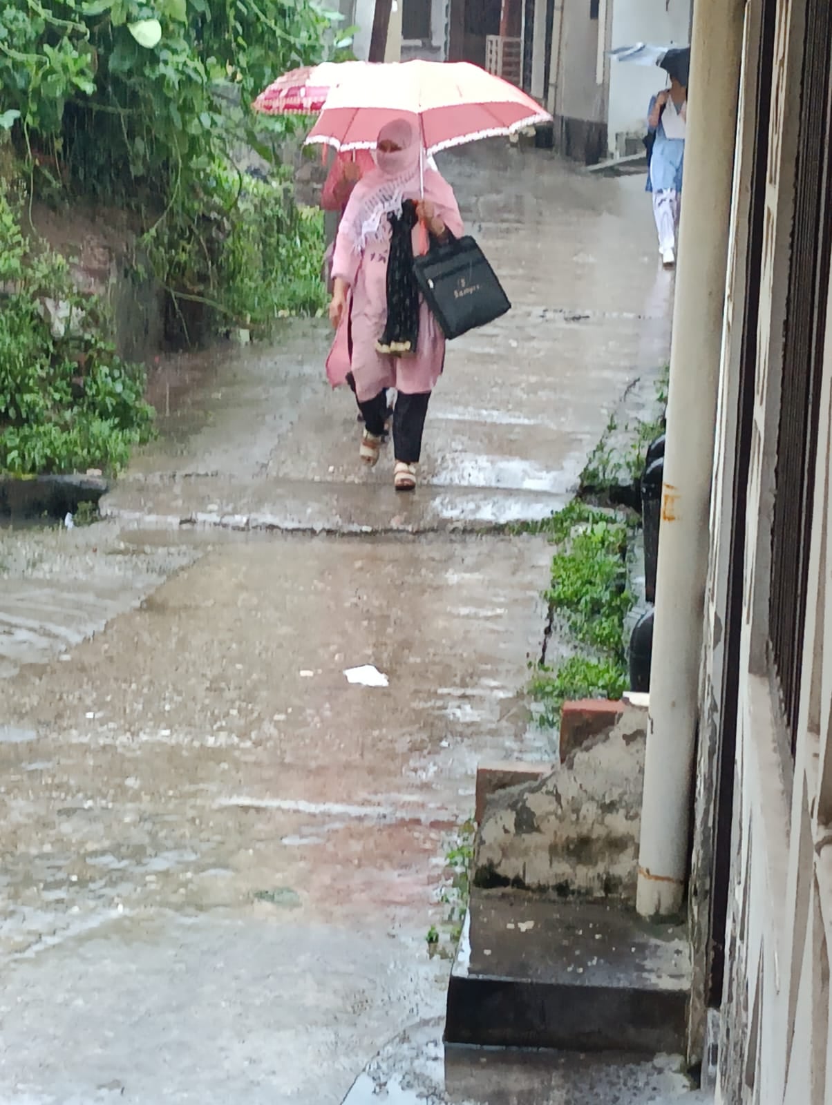 बारिश में रेनकोट पहनकर जाते लोग । संवाद