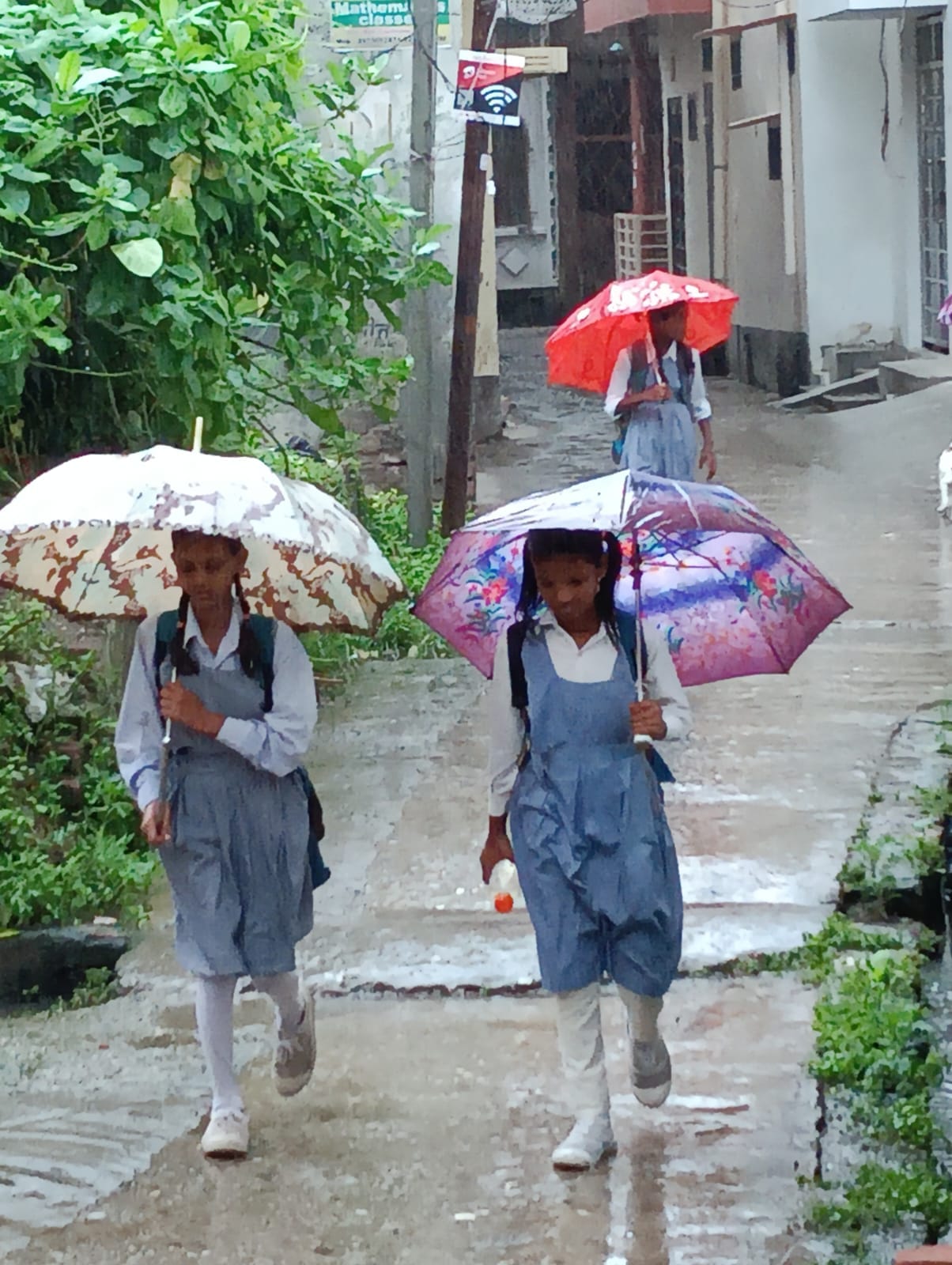 बारिश में रेनकोट पहनकर जाते लोग । संवाद
