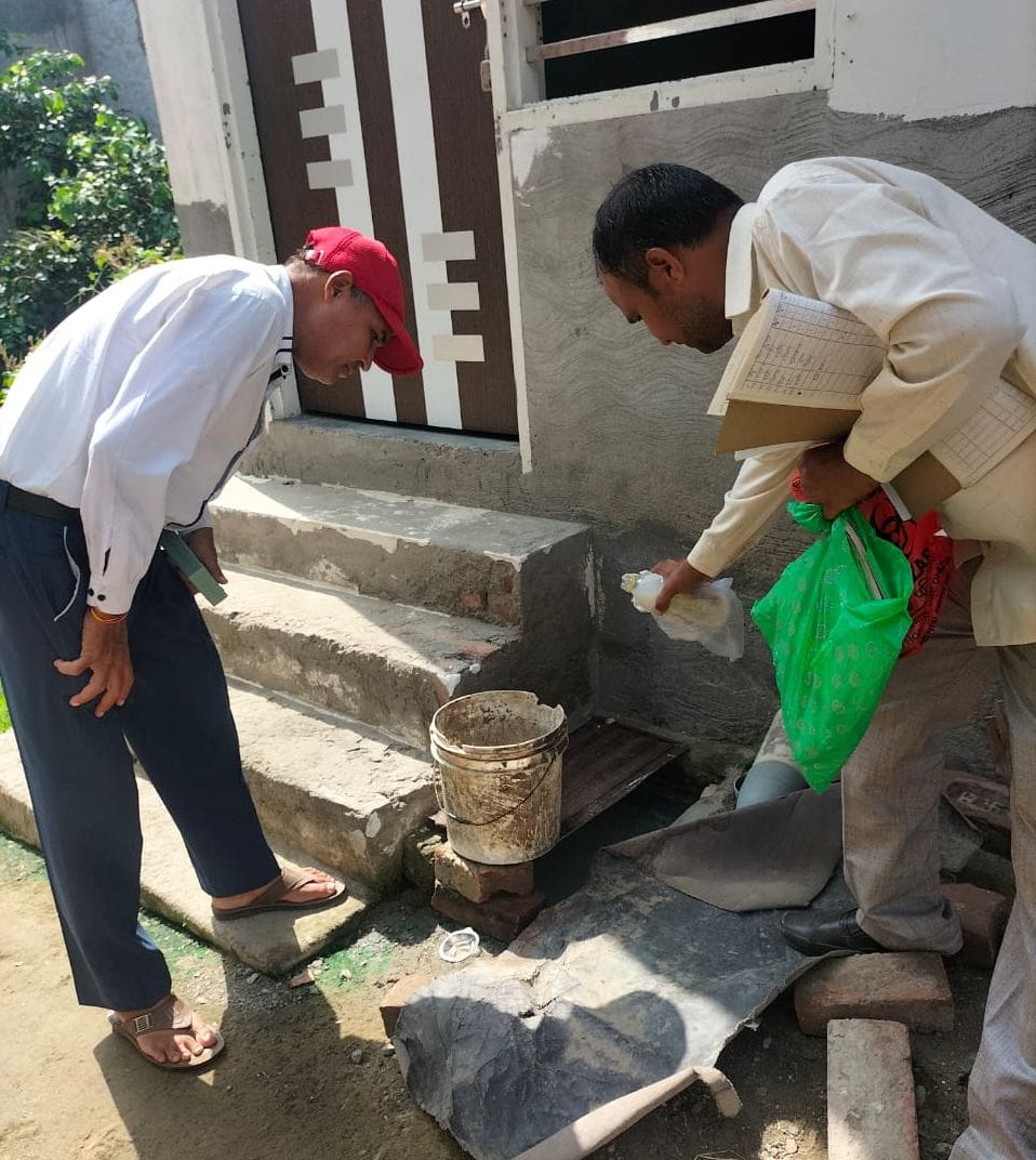 फोटो 14. डोर-टू-डोर सर्वे के दौरान बर्तन में भरे पानी में लार्वा खत्म करने की दवा डालते स्वास्थ