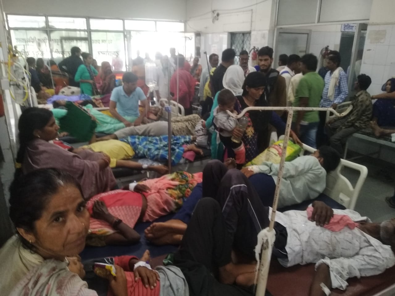 शाहजहांपुर में ट्रामा सेंटर में गर्मी के चलते हाथ में पंखा लिए खड़ी महिला