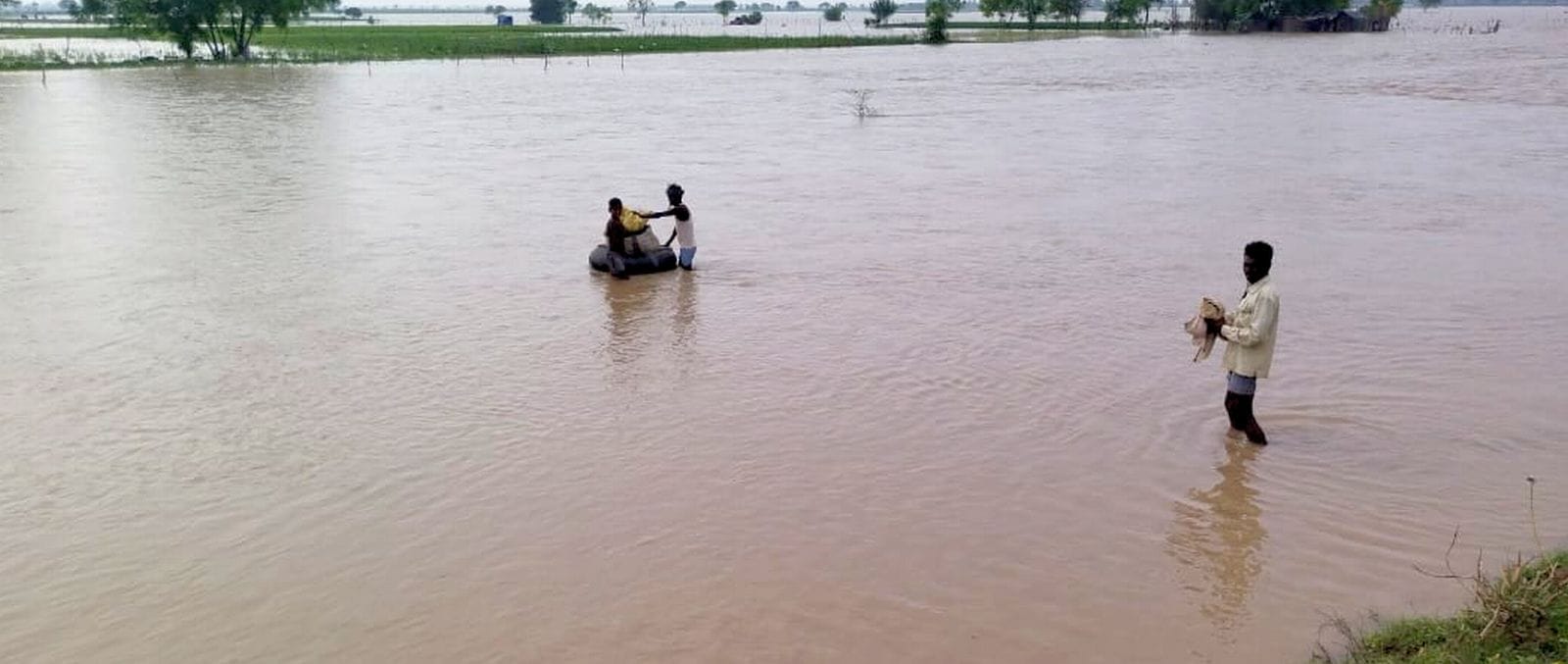 नगरिया खनू में खेतो में भरा बाढ़ के पानी के बीच नांव से जाते लोग। संवाद