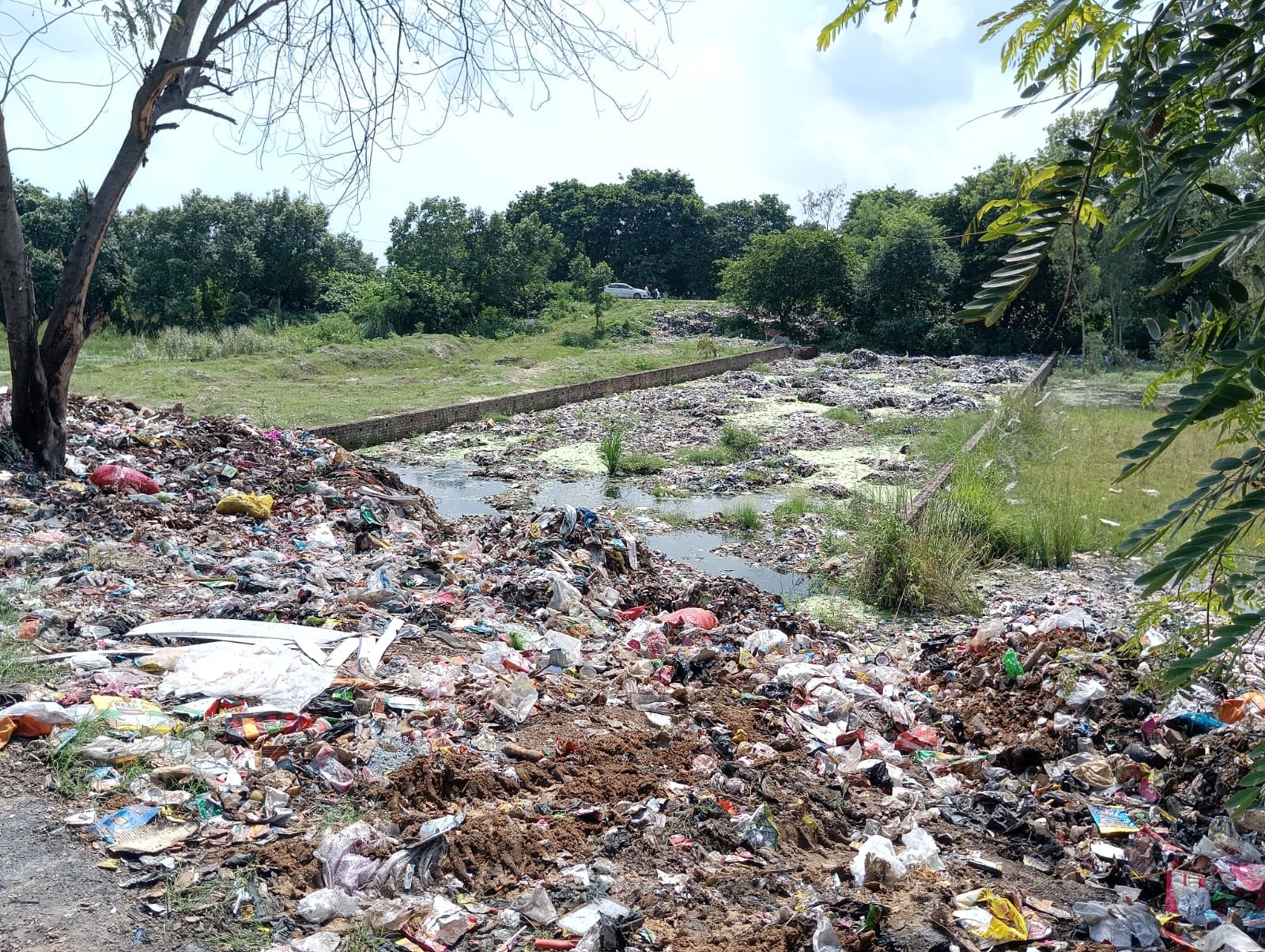 शहर की र्ददगाह रेलवे क्रांसिग से बरेली जाने वाली रोड किनाारे एक खाली जगह पर लगा कूड़े का ढ़ेर ।