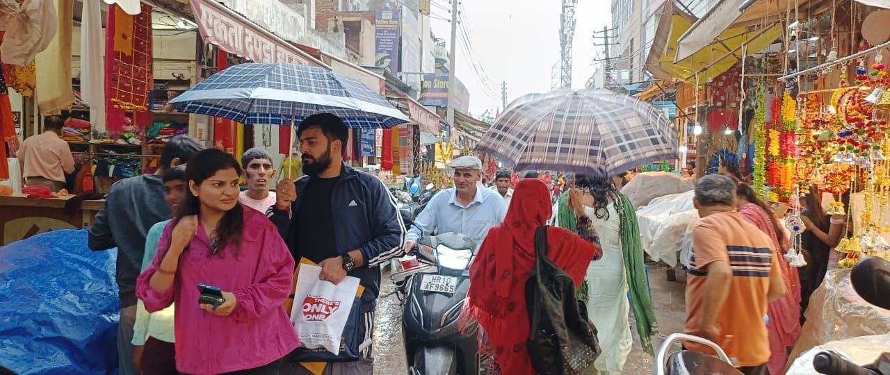 फोटो :44: सोनीपत में शुक्रवार को बूंदाबांदी के बीच छाता लेकर बाजार में खरीदारी करने आए ग्राहक। 