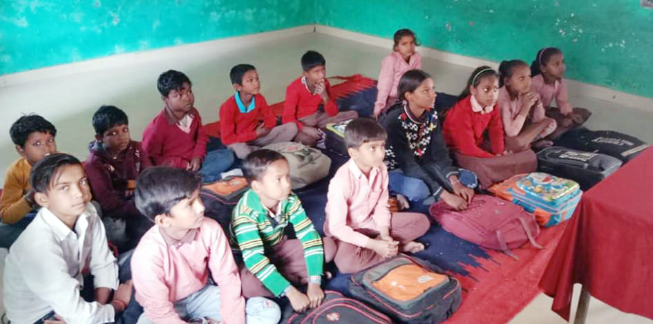 गोला के त्रिलोक गिरी सम्मेलन विद्यालय में चटाई पर बैठकर पढ़ते विद्यार्थी।