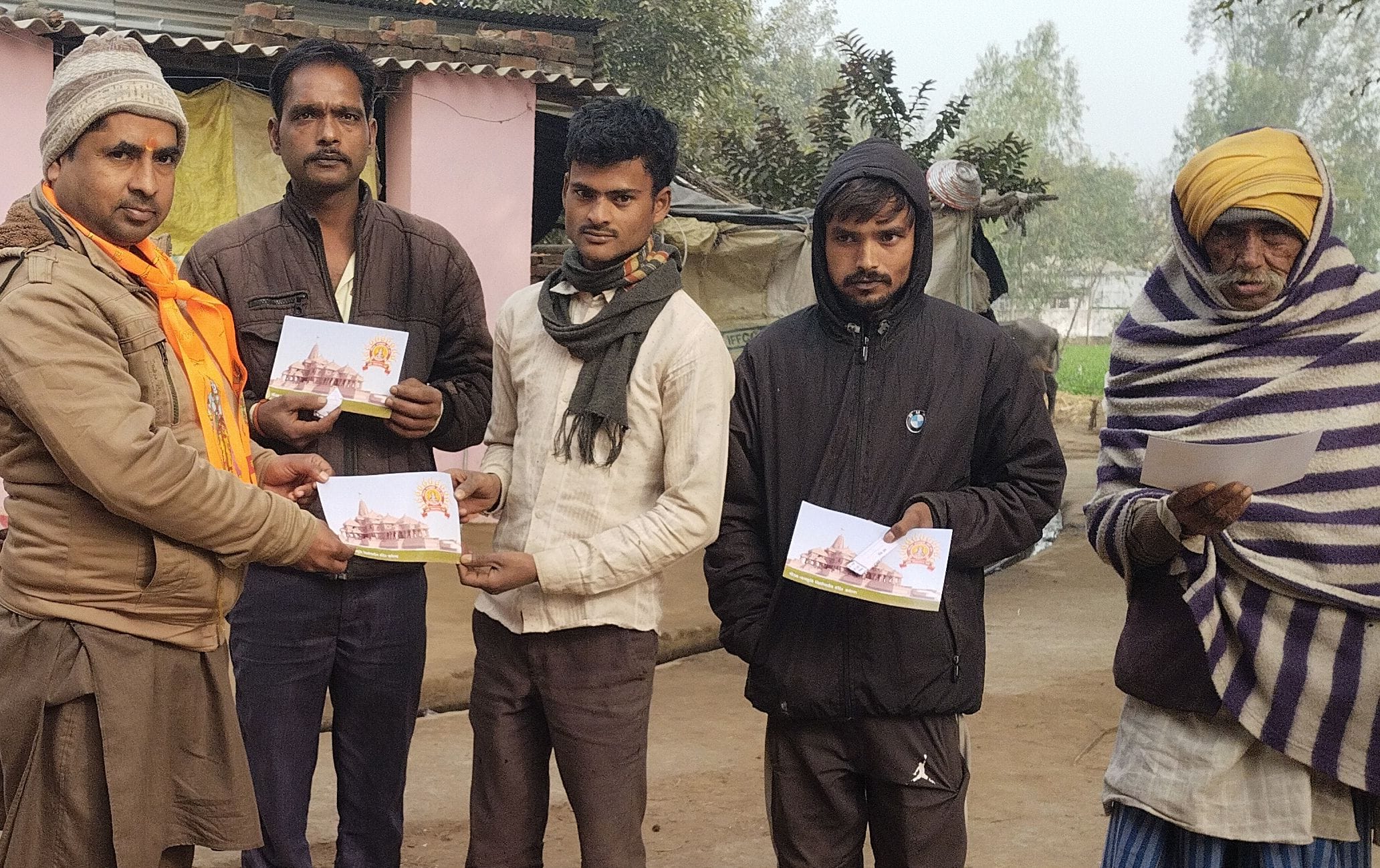 तिलहर के गांव सुरेली में संघ कार्यकर्ता ग्रामीणों को अक्षत और पत्रक वितरित करते हुए