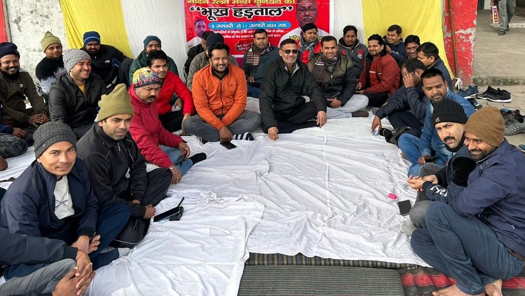 रेलवे स्टेशन के प्लेटफॉर्म नंबर एक पर क्रमिक भूख हड़ताल पर बैठे शिक्षक-कर्मचारी। संवाद