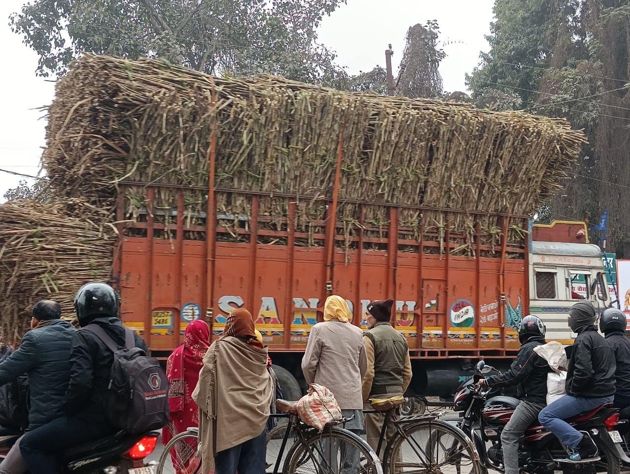 शहर के गौंहनिया चौराहे से गुजरते गन्ना लदे ट्रक । संवाद