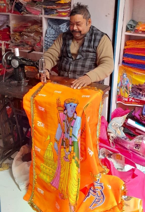 सरायअकिल बाजार में भगवा झंडे की सिलाई करता दर्जी।      संवाद