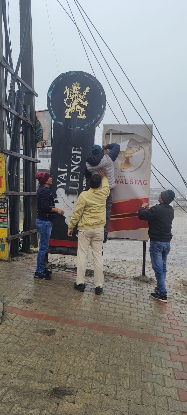 01जेएनडी40 : शराब ठेकों के बाहर लगे विभिन्न ब्रांडों के होर्डिंग्स उतारते हुए कर्मी। स्वयं