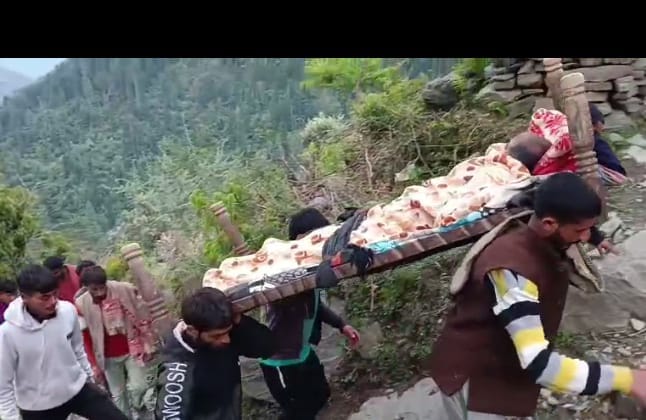 आयल पंचायत में बीमार व्यक्ति को चारपाई पर लेकर जाते परिजन। संवाद आयल पंचायत में बीमार व्यक्ति को चारपाई पर लेकर जाते परिजन। संवाद