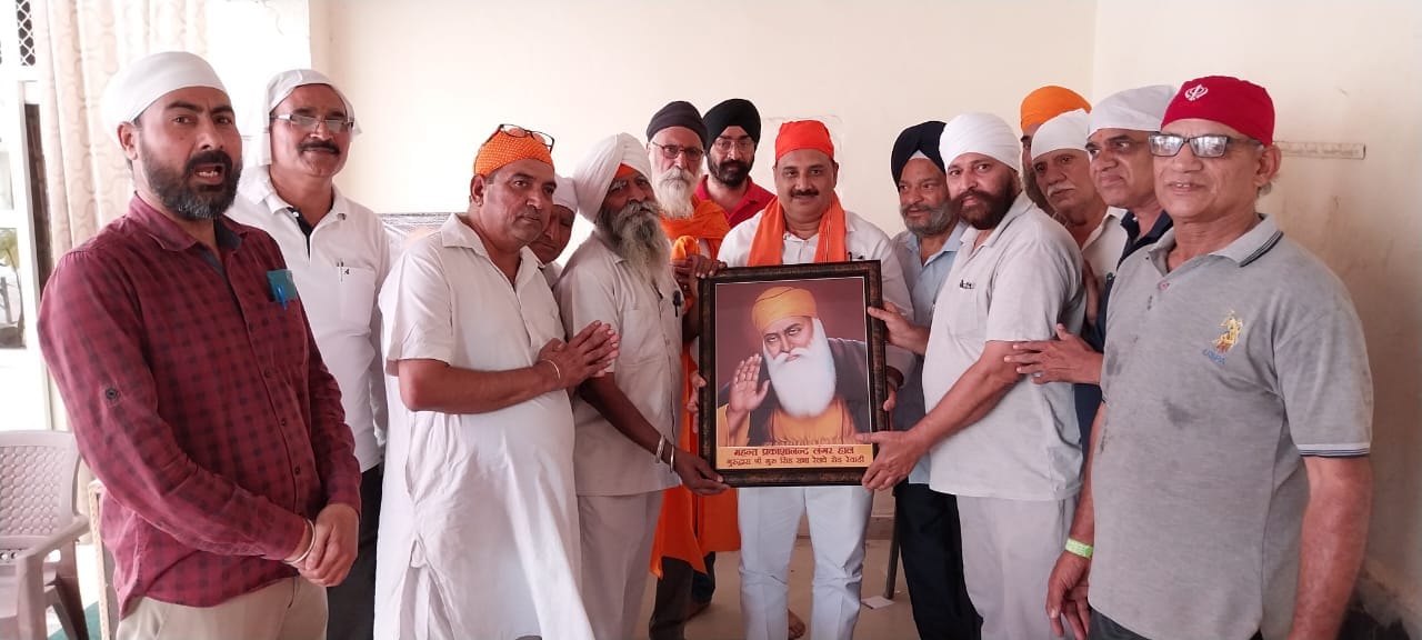 रेवाड़ी। कार्यक्रम में डॉ. सतीश खोला को गुरु जी का चित्र भेंट करते हुए। स्रोत : पीआरओ