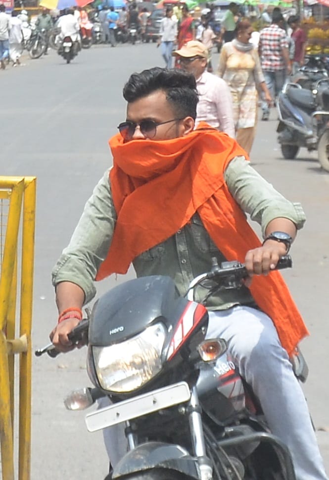 तेज धूप से बचने के लिए मुंह पर गमछा लपेटकर जाते युवा। संवाद तेज धूप से बचने के लिए मुंह पर गमछा लपेटकर जाते युवा। संवाद
