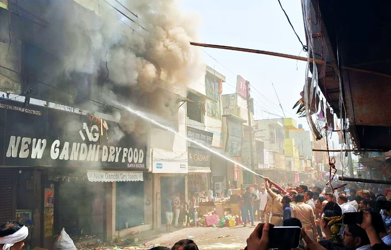 दुकान के अंदर लगी आग के बीच सामान निकालते दुकानदार। संवाद दुकान के अंदर लगी आग के बीच सामान निकालते दुकानदार। संवाद