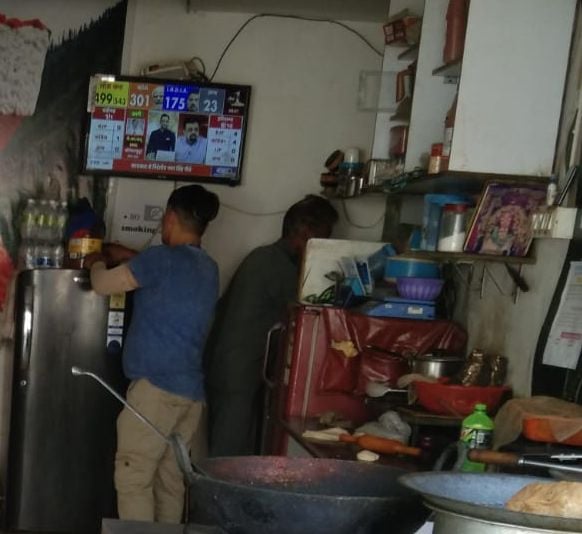 मंडी शहर में मतगणना  के रूझानों को फोन पर देखते लोग