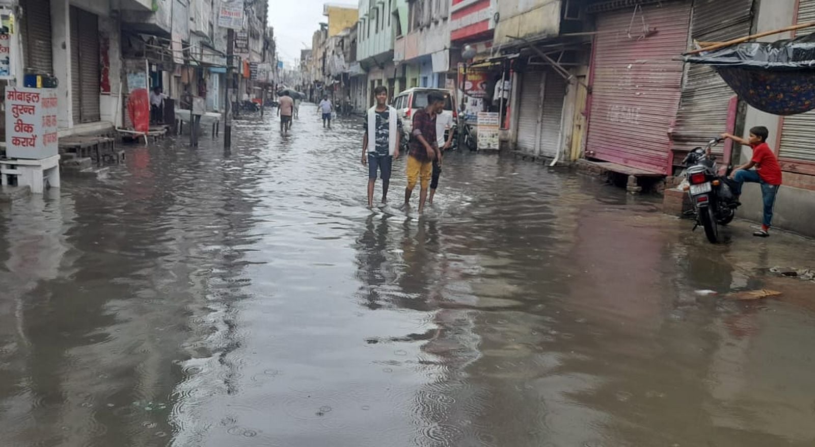 प्राइवेट बस स्टैंड पर कीचड़ से होकर बस चढ़ते यात्री। संवाद
