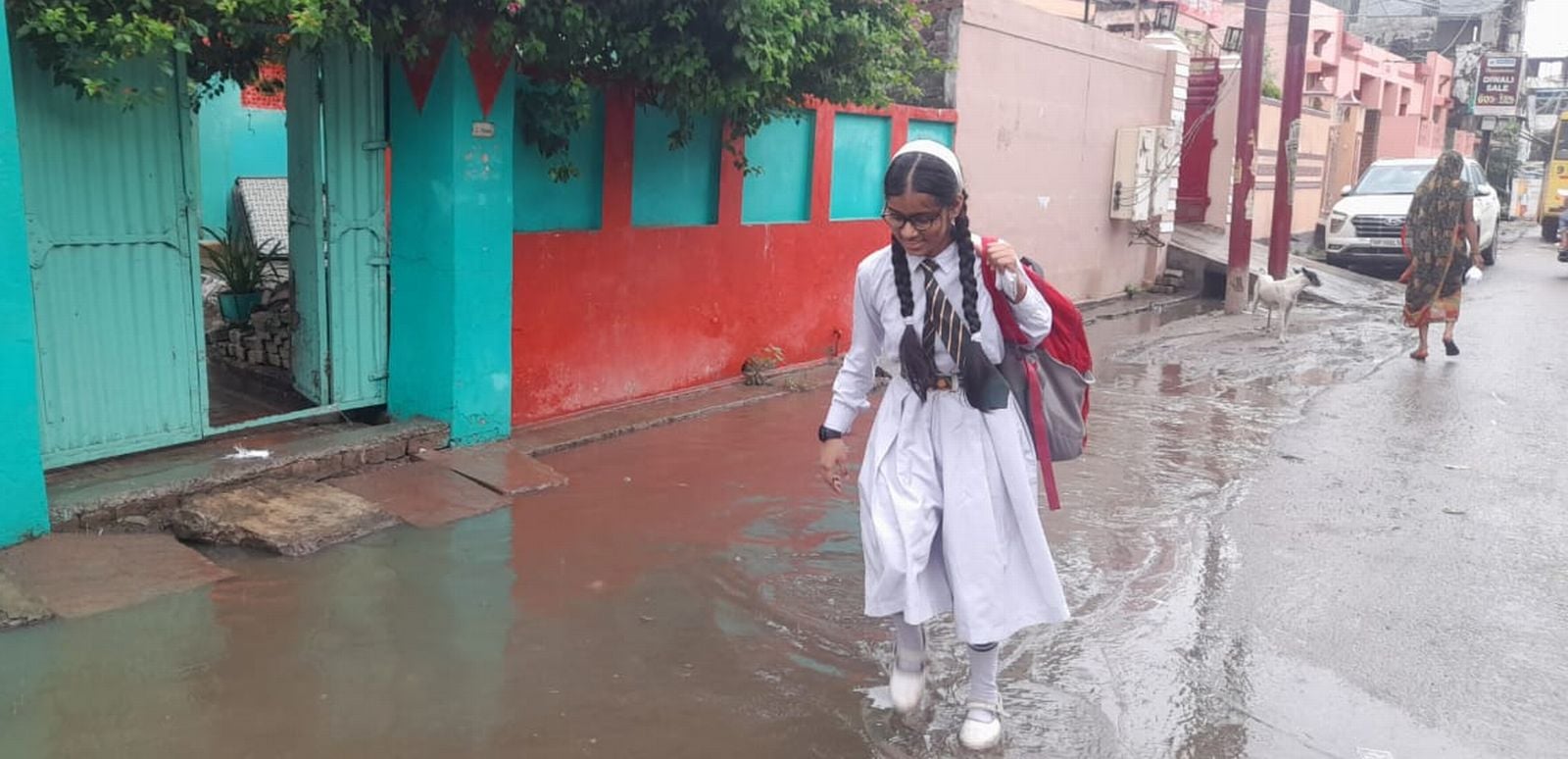 प्राइवेट बस स्टैंड पर कीचड़ से होकर बस चढ़ते यात्री। संवाद