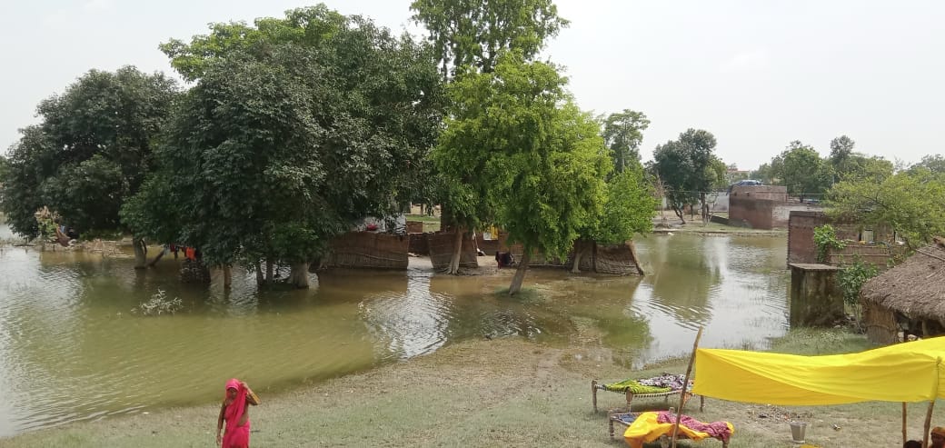 लुधौनी गांव में सड़क किनारे छाता लगाकर बैठी बाढ़ पीड़ित महिला। संवाद