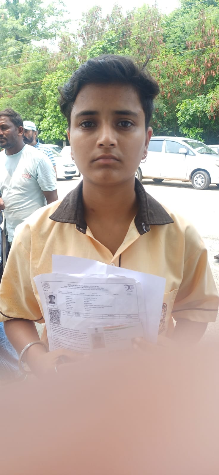 स्कूल के बाहर खडे़ परिक्षार्थी आधार कार्ड की कॉपी दिखाते हुए।