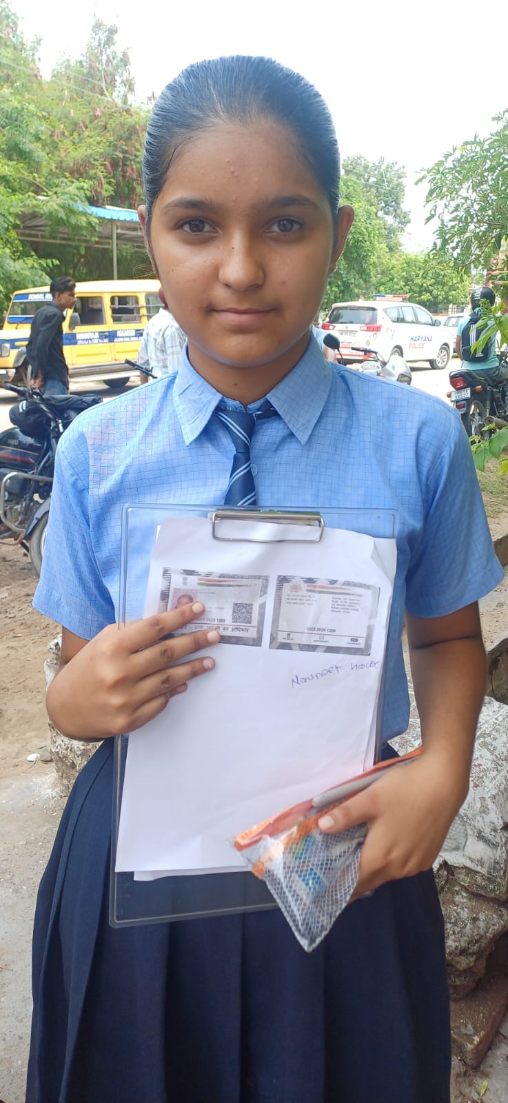 स्कूल के बाहर खडे़ परिक्षार्थी आधार कार्ड की कॉपी दिखाते हुए।