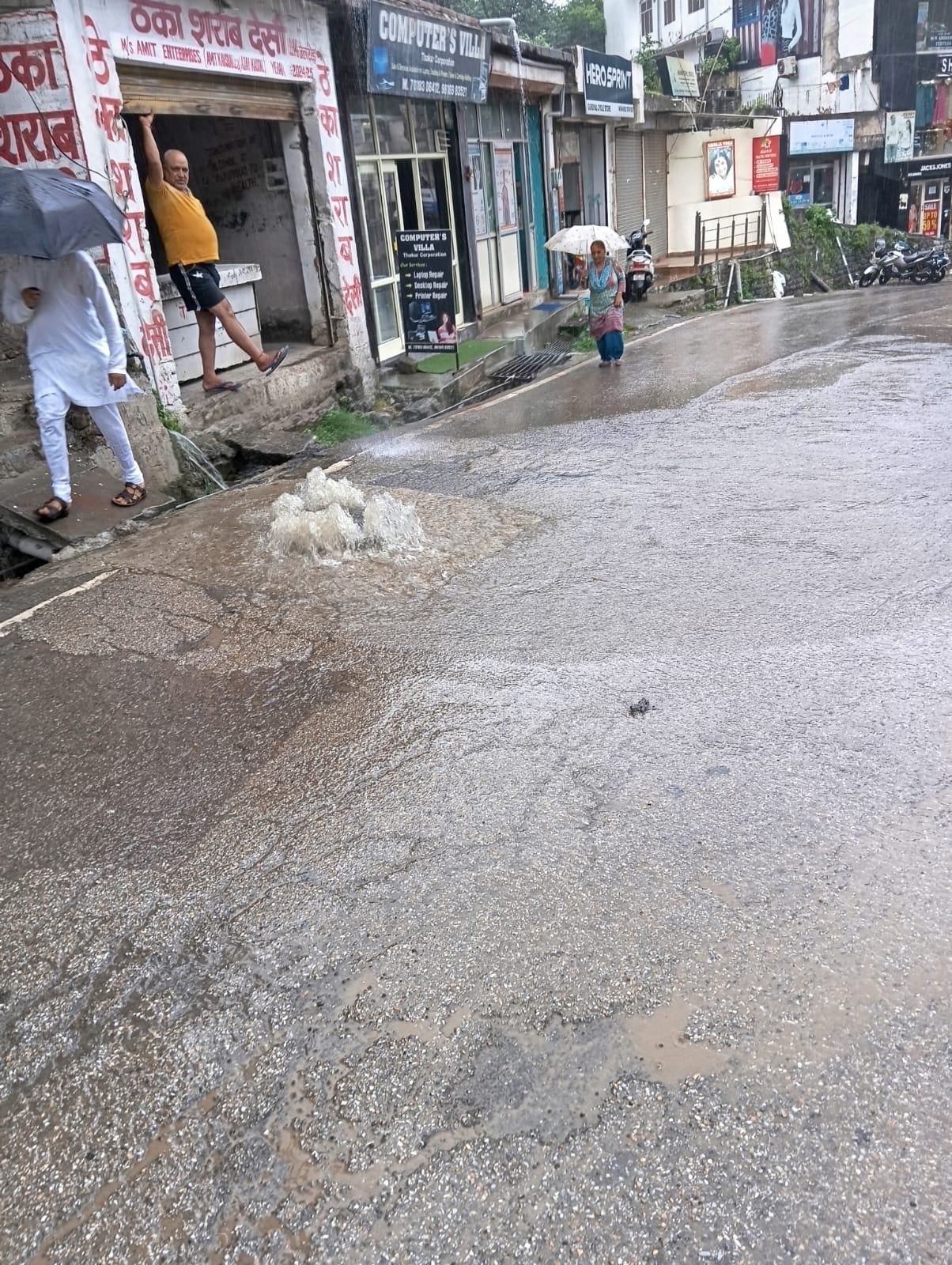 मंडी के चौहाटा बाजार में बारिश के दौरान छाता लेकर अपने गंतव्य की ओर जाते लोग   संवाद