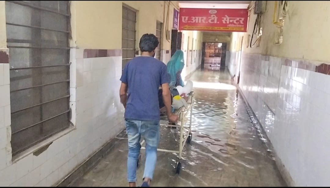 अस्पताल परिसर में भरे पानी से गुजरते मरीज अस्पताल परिसर में भरे पानी से गुजरते मरीज