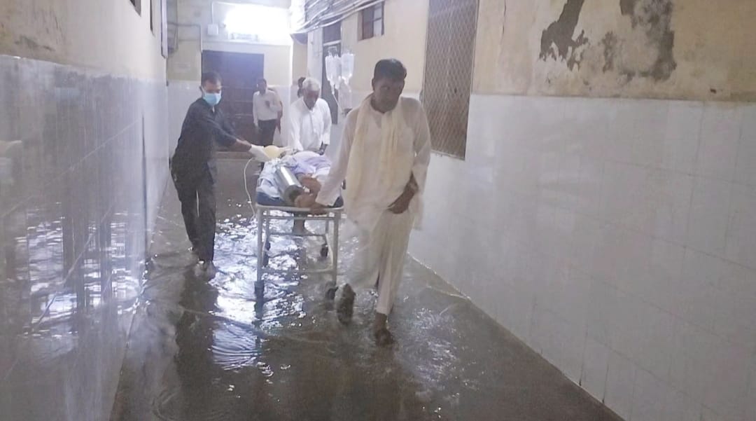 अस्पताल परिसर में भरे पानी से गुजरते मरीज अस्पताल परिसर में भरे पानी से गुजरते मरीज