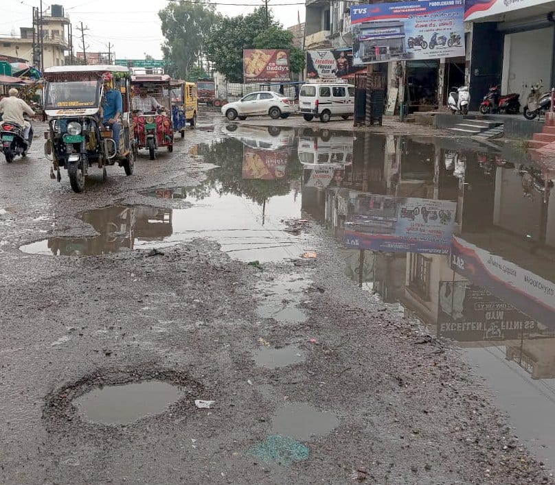 शामली  के दिल्ली रोड पर सीटी  ग्रीन के सामने टूटी सडक से गुजरते वाहन । संवाद