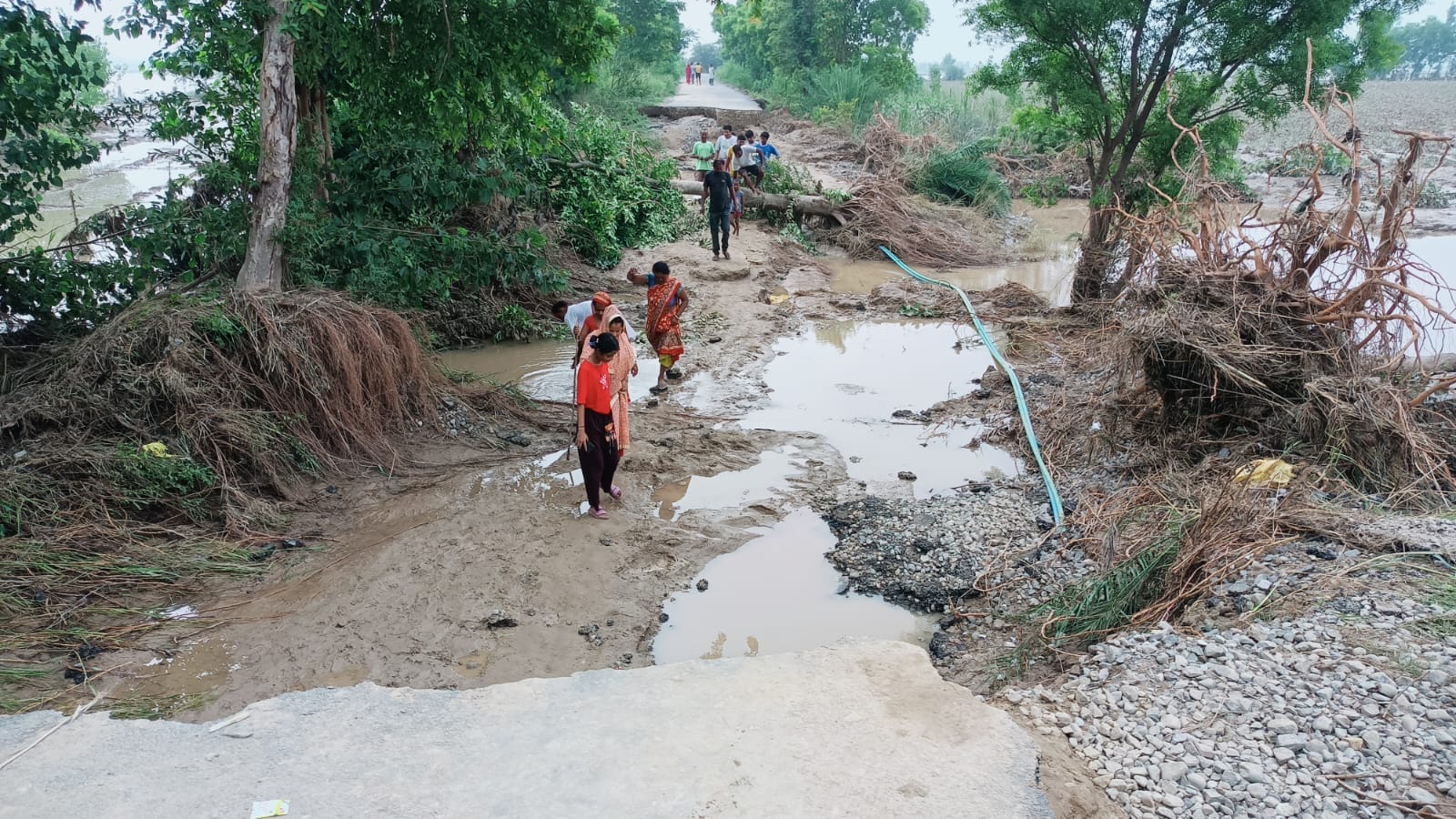माधोटांडा मार्ग पर बाढ़ में कटे मार्ग पर असुविधाओं के बीच गुजरते राहगीर। संवाद