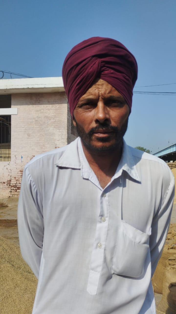 स्थान न होने के कारण मंडी की सड़क पर धान उतारते हुए किसान। स्थान न होने के कारण मंडी की सड़क पर