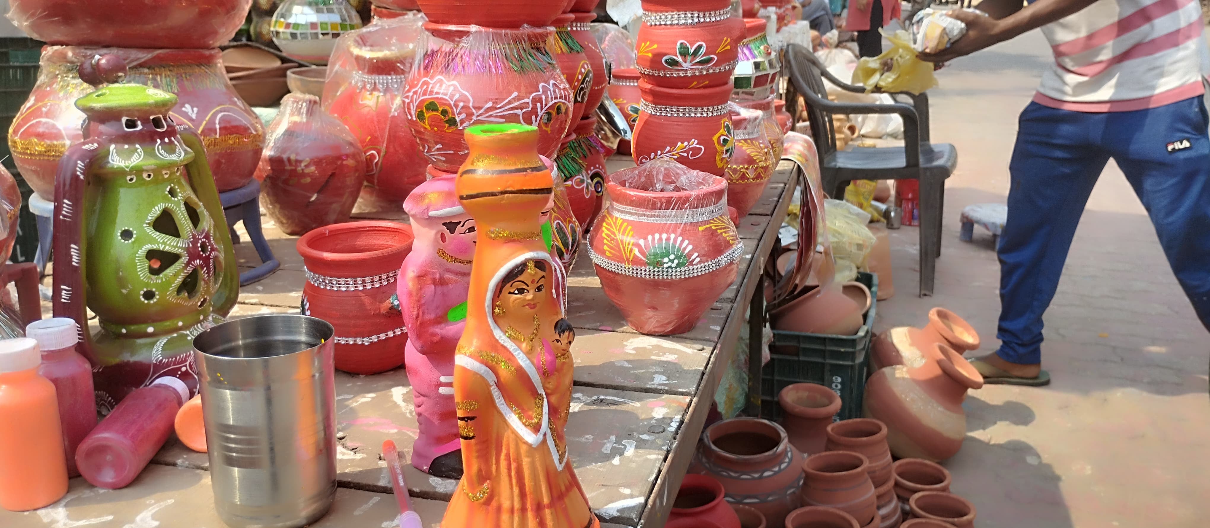 शहर में बर्तन को आकर्षक रंग में सजाता व्यक्ति।