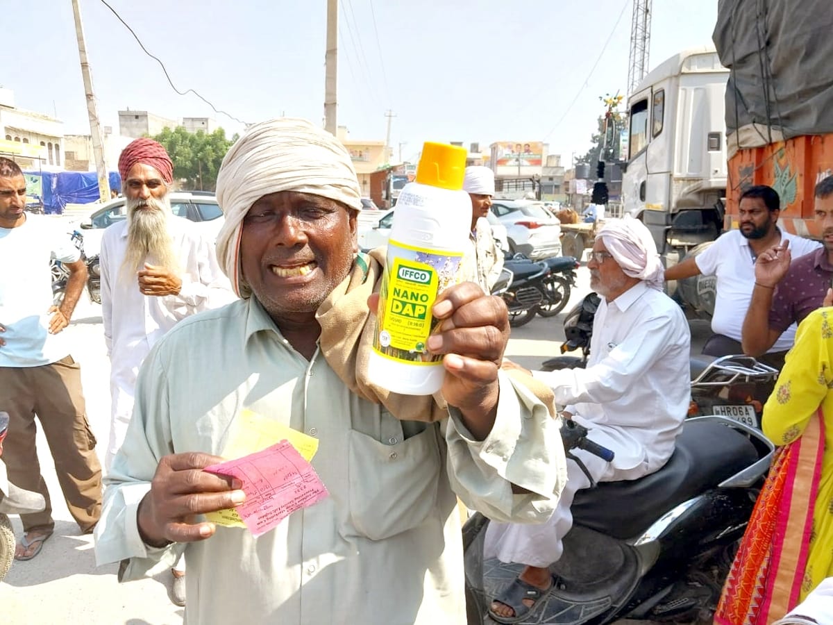 24जेएनडी24: खाद के साथ दी जा रही शीशी को दिखाता हुआ एक किसान। संवाद