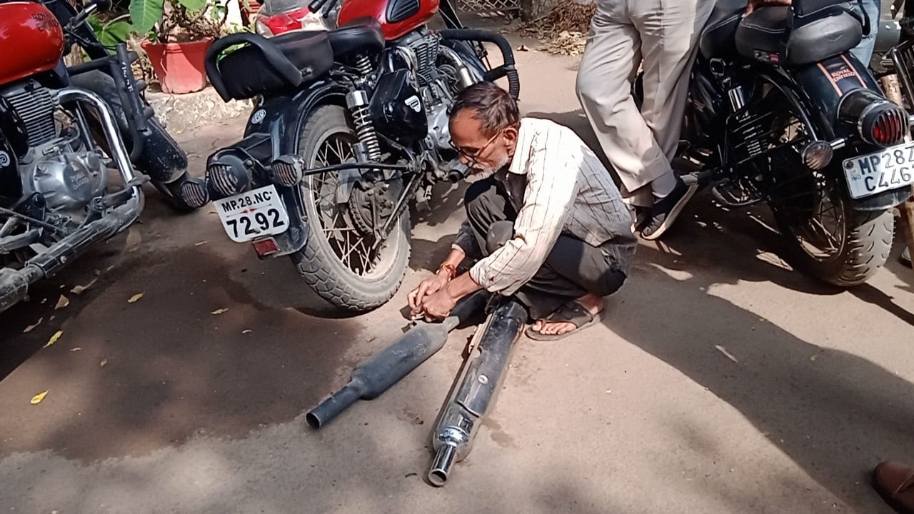 बुलेट से साइलेंसर निकालते हुए पुलिस कर्मी