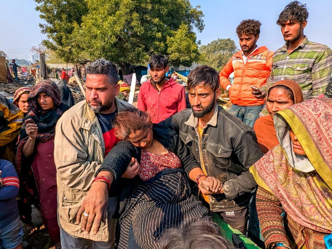 झुग्गी गिरने के बाद मेमने लिए खड़ीं बच्चियां।