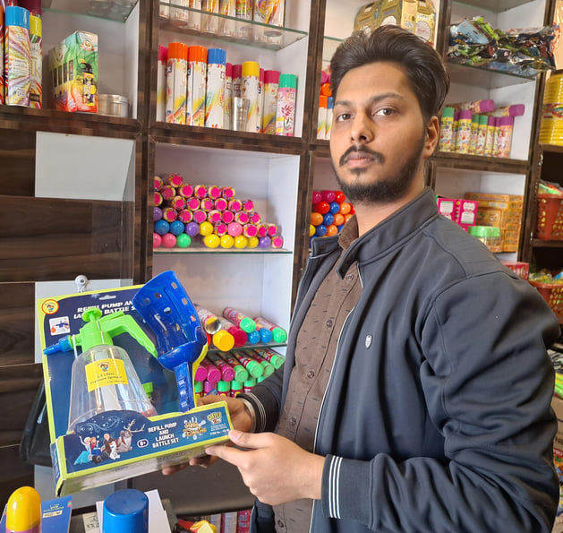 109-कैथल। होली पर बाजार में अपने परिजनों के साथ पिचकारी खरीदते बालक। संवाद