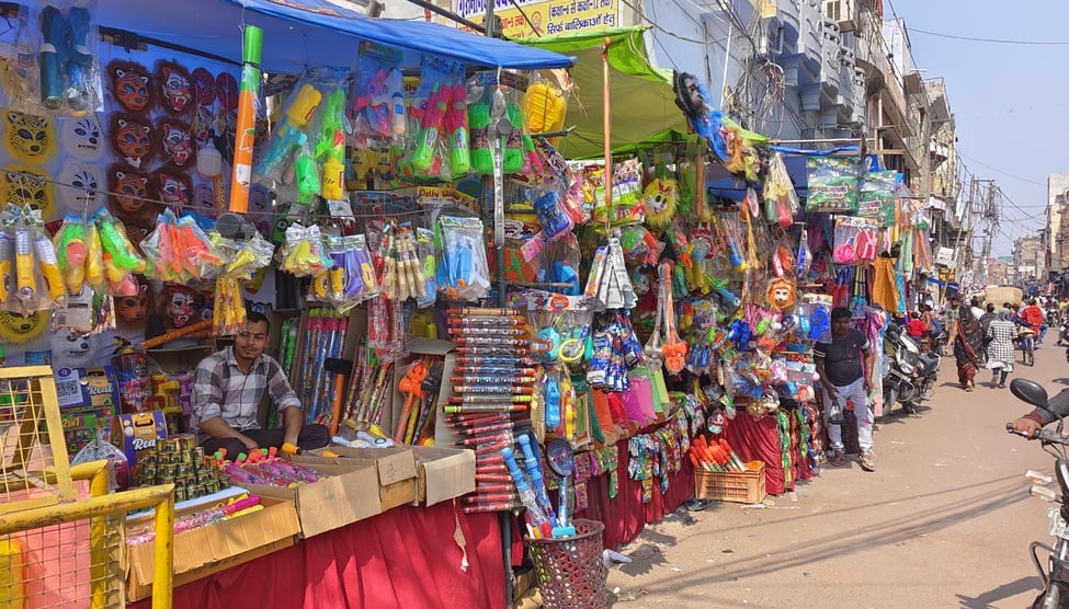 रंग गुलाल और मुखौटे आदि खरीदते लोग। संवाद
