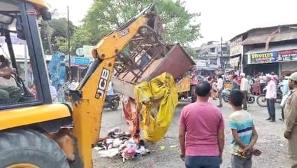 अतिक्रमण हटाते हुए जेसीबी से टीन शेड और चबूतरे तोड़ती प्रशासनिक टीम