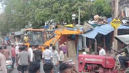 अतिक्रमण हटाते हुए जेसीबी से टीन शेड और चबूतरे तोड़ती प्रशासनिक टीम
