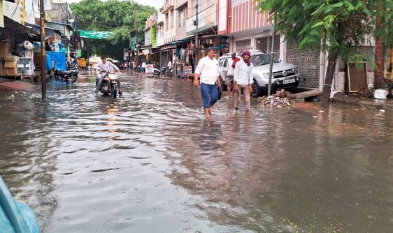 बारिश में छाता लगाकर जाते बाइक सवार। संवाद बारिश में छाता लगाकर जाते बाइक सवार। संवाद