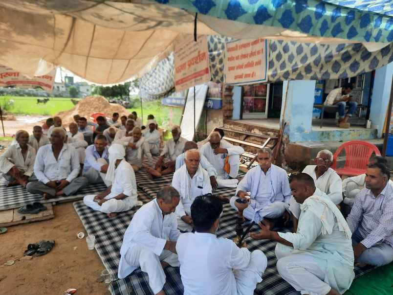 फोटो : 17अस्पताल बनाने की मांग के लिए गांव के बस स्टैंड के पास धरने पर बैठे ग्रामीण। स्रोत : सम