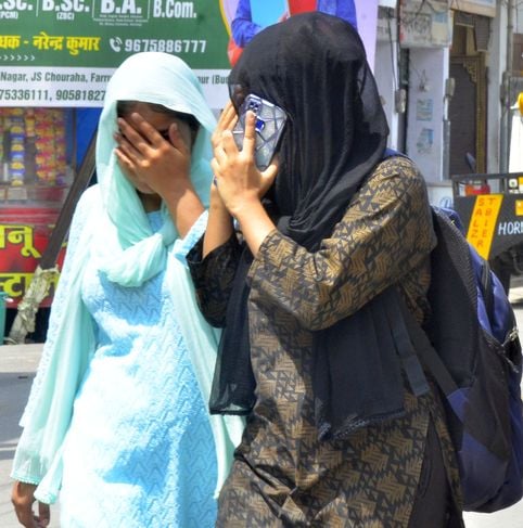 धूप में छाता लगाकर कोतवाली रोड से गुजरती युवती। संवाद