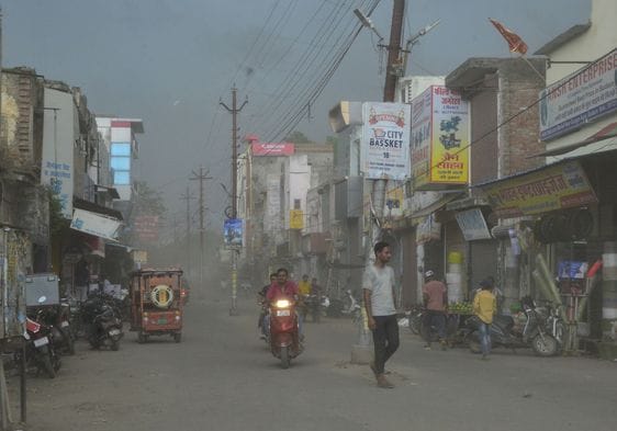 बारिश में छाता लगाकर जाते स्कूटी सवार। संवाद