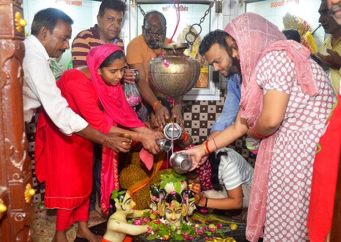 बिरूआबाड़ी मंदिर में भोलेनाथ का जलाभिषेक करते शिव भक्त। संवाद